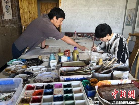 圖為2020年8月下旬，敦煌“80后”畫家張杰龍(左)在為云南麗江“學(xué)生”莫北講解敦煌壁畫的繪畫技巧?！●T志軍 攝