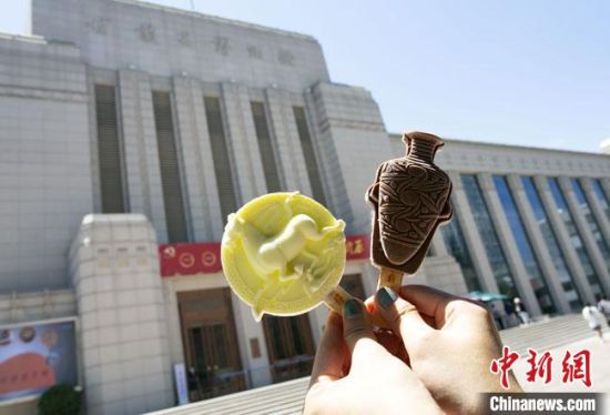 2021年7月30日，游客手拿“銅奔馬”“彩陶瓶”造型的雪糕，在甘肅省博物館前拍照打卡?！「哒?攝