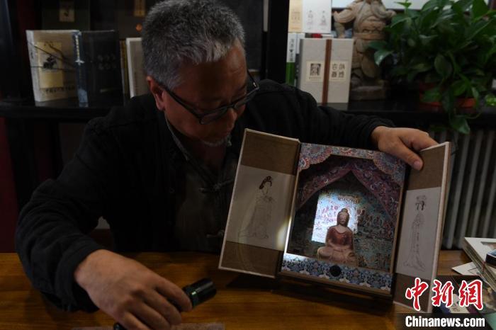 圖為讀者出版集團(tuán)讀者晉林工作室獨(dú)立出品人徐晉林，展示互動性強(qiáng)的敦煌題材手工書。(資料圖) 楊艷敏 攝