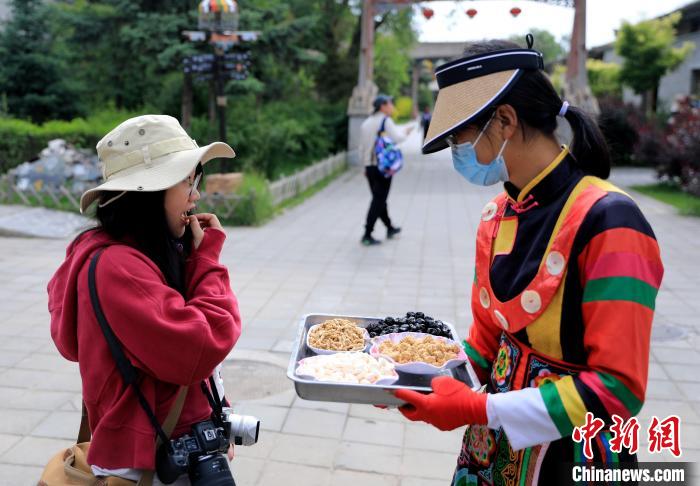 圖為身穿土族服飾的女性介紹當(dāng)?shù)靥厣〕浴！⊙Φ?攝