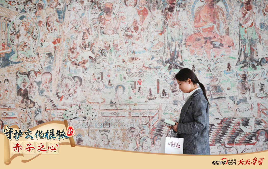 2023年4月25日，敦煌研究院文物數(shù)字化保護(hù)團隊創(chuàng)意營銷人員廖雪婷從一幅高保真復(fù)制壁畫前走過。