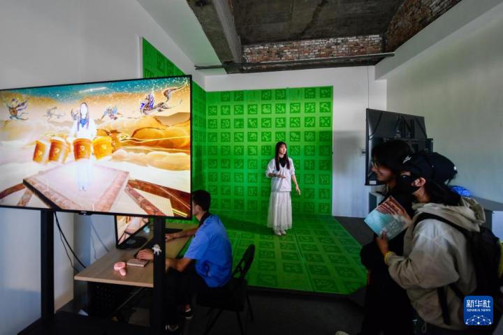 7月22日，游客體驗(yàn)“尋境敦煌——數(shù)字敦煌沉浸展”后，在虛擬演播廳拍攝一段真人與洞窟虛擬場(chǎng)景交互的視頻。新華社記者 郎兵兵 攝</p>
<p>